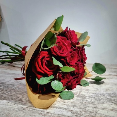 Bouquet de rosas vermelhas com folhagem verde e papel castanho