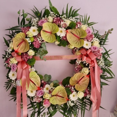 coroa fúnebre colorida com flores e fita rosa