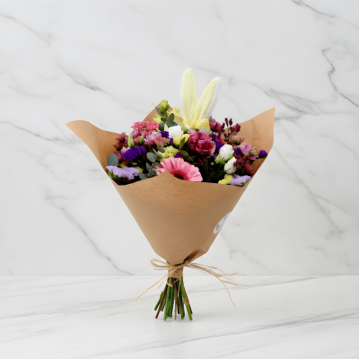 Buquê de flores coloridas embalado em papel castanho claro com laço de ráfia