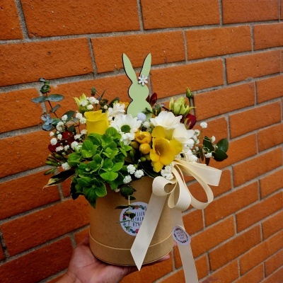 Arranjo floral com coelho decorativo em vaso de papel castanho com fita bege