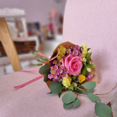 Buquê de flores coloridas numa cadeira rosa claro