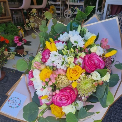 Bouquet colorido de flores variadas embalado em papel bege com bordas brancas