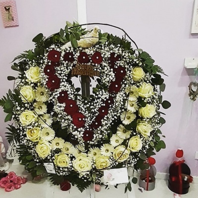 Coroa fúnebre floral com cruz e coração de flores vermelhas no centro