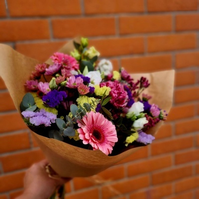 Buquê de flores coloridas em papel kraft com fundo de parede de tijolos.