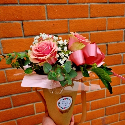 Pequeno bouquet de flores com rosas cor-de-rosa e fita cor-de-rosa em embalagem de papel castanho