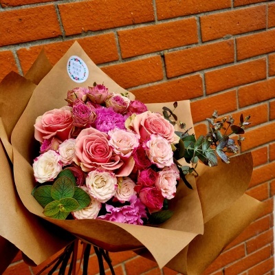 Buquê de flores rosas e brancas embalado em papel castanho