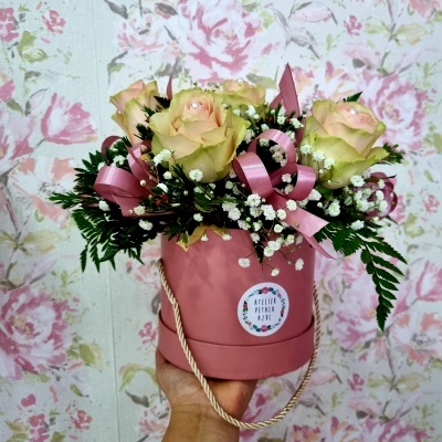 Arranjo floral com rosas amarelas num vaso rosa fosco, com fundo floral rosa
