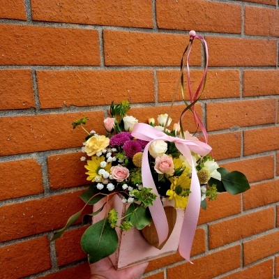 Arranjo floral colorido em vaso suspenso rosa com fita decorativa