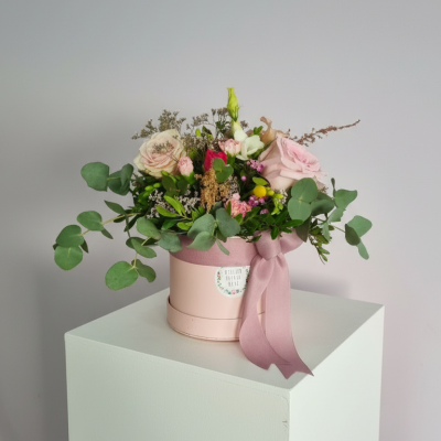 Arranjo floral em caixa redonda rosa com fita rosa em pedestal branco