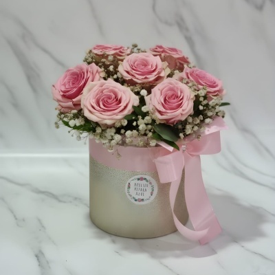 Arranjo floral em caixa com rosas cor de rosa e pequenas flores brancas