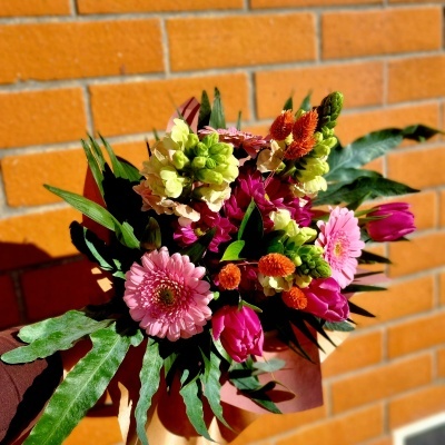 Bouquet de flores multicolor com papel castanho e fundo de parede de tijolos