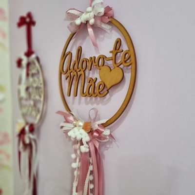 Enfeite decorativo em madeira com a frase 'Adoro-te Mãe' e adornos cor de rosa e branco