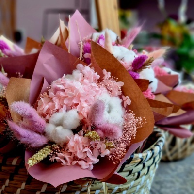 Bouquet de flores secas em papel castanho e rosa dentro de um cesto de palha