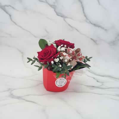Arranjo floral com rosas vermelhas e folhagem em vaso vermelho