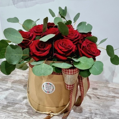 Buquê de rosas vermelhas com folhas verdes em vaso decorativo de tecido bege