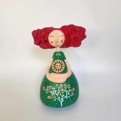 Boneca decorativa de madeira com cabelo vermelho e vestido verde com padrão floral