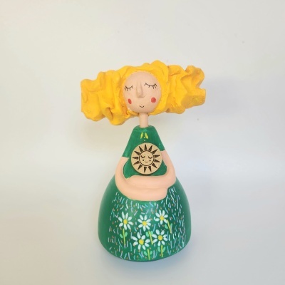 Figura decorativa em cerâmica de mulher com cabelo amarelo e vestido verde com flores