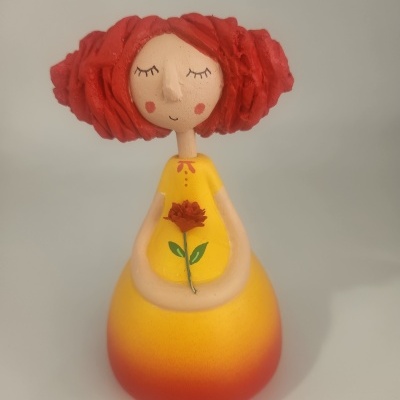 Boneca decorativa amarela com cabelo vermelho e flor pintada