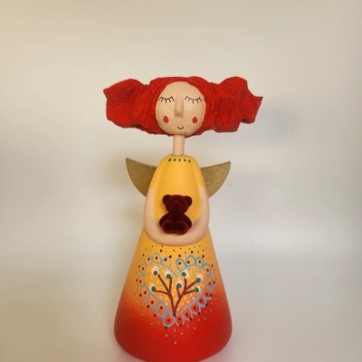 Figura decorativa em forma de anjo com vestido amarelo e vermelho e cabelo vermelho