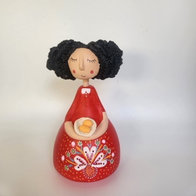 Figurinha de cerâmica com vestido vermelho e decoração floral a segurar prato com ovos