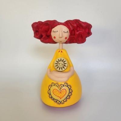Figura decorativa com cabelo vermelho e vestido amarelo com coração e sol