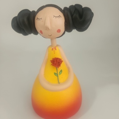 Estatueta decorativa de menina com vestido amarelo e cabelo preto em coques.