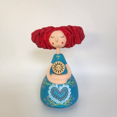 Boneca de cerâmica colorida com cabelo vermelho e vestido azul decorado com padrões florais e coração