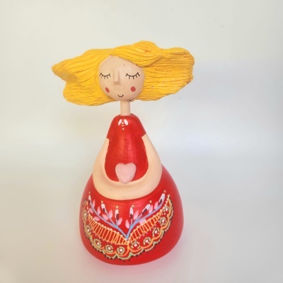 Figura decorativa em madeira com vestido vermelho e cabelo amarelo