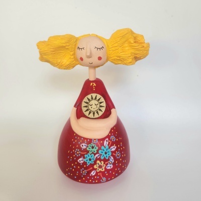 Figura decorativa de menina com cabelo amarelo e vestido vermelho com padrão floral