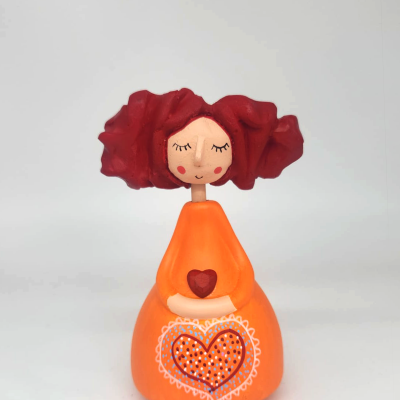 Figura decorativa de menina com vestido laranja e cabelo vermelho