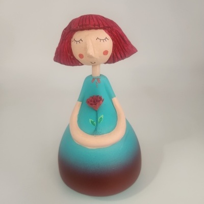 Estatueta decorativa de menina com cabelo vermelho e vestido azul segurando flor vermelha