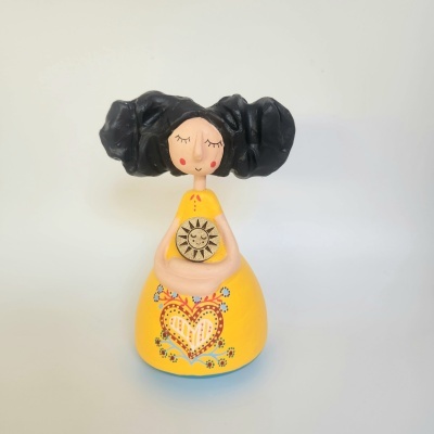 Figura decorativa de mulher com vestido amarelo e cabelo preto