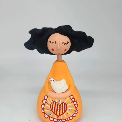 Figurinha decorativa em cerâmica de mulher com vestido amarelo e pássaro branco