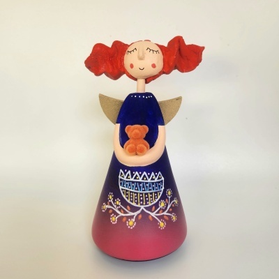 Boneca decorativa com vestido colorido e cabelo vermelho em fundo branco.