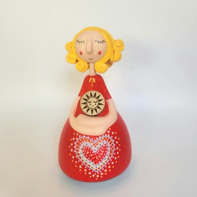 Figura decorativa vermelha com cabelo amarelo e coração pintado