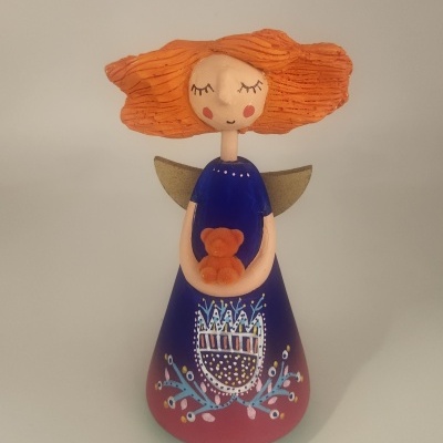 Anjo decorativo com vestido azul e cabelo laranja segurando ursinho