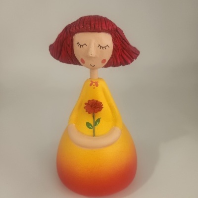 Figura decorativa de cerâmica com vestido amarelo e laranja e cabelo vermelho
