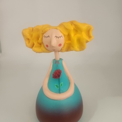 Boneca decorativa cerâmica com vestido azul e castanho e cabelo amarelo cacheado