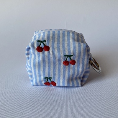 Bolsa pequena azul com riscas brancas e bordados de cerejas vermelhas.