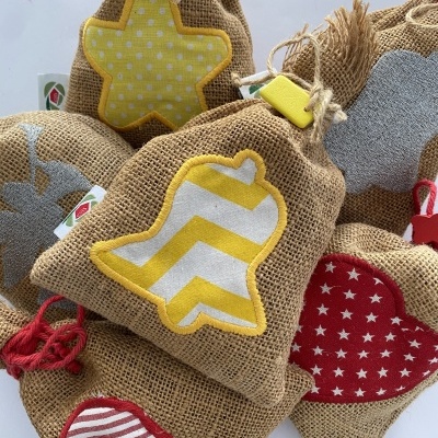 Sacolas decorativas de juta com aplicações de tecido colorido em vários padrões e formas festivas.