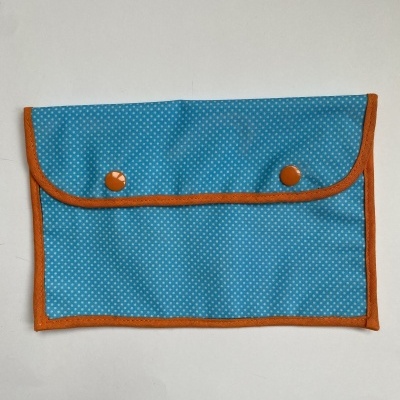 Estojo azul com pontos brancos e bordas laranja com botões de pressão