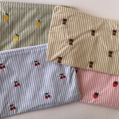 Quatro sacos de tecido com padrão riscado e bordados de frutas e ursos