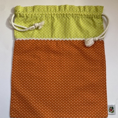 Saco de tecido verde lima e laranja com padrão de pontos brancos e cordão branco
