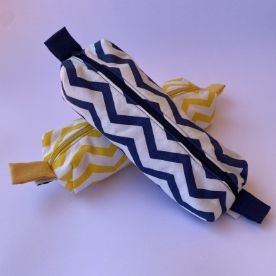 Bolsas cilíndricas com padrão ziguezague azul e amarelo em fundo branco