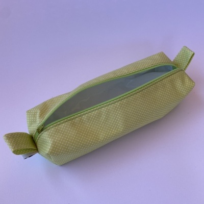 Estojo retangular amarelo com pontos brancos e fecho verde sobre fundo branco