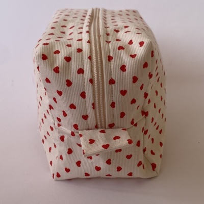 Necessaire creme com corações vermelhos e fecho de correr