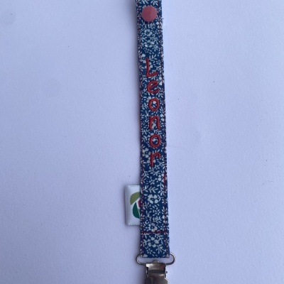 Prendedor de chupeta azul floral com nome Leonor bordado