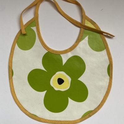 Babete para bebé com padrão de flores verdes e amarelas