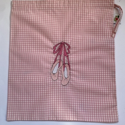 Saco de tecido rosa com padrão de quadrados e bordado de sapatilhas de balé
