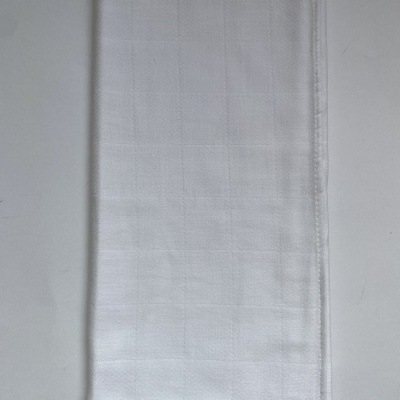 Toalha branca quadriculada dobrada sobre superfície branca